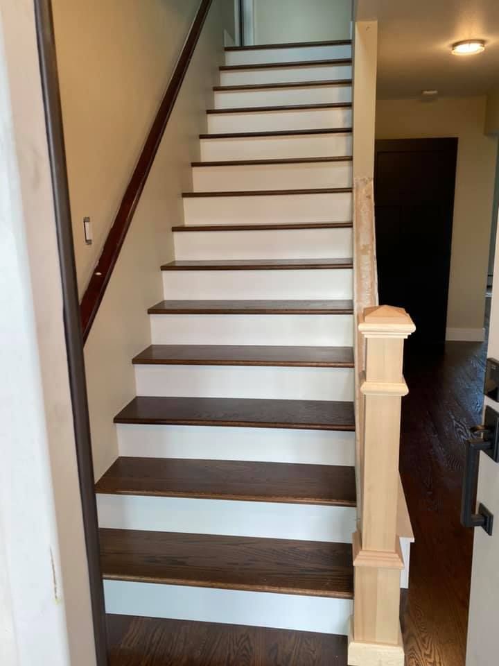 A wooden staircase with white steps and a wooden railing in a house.