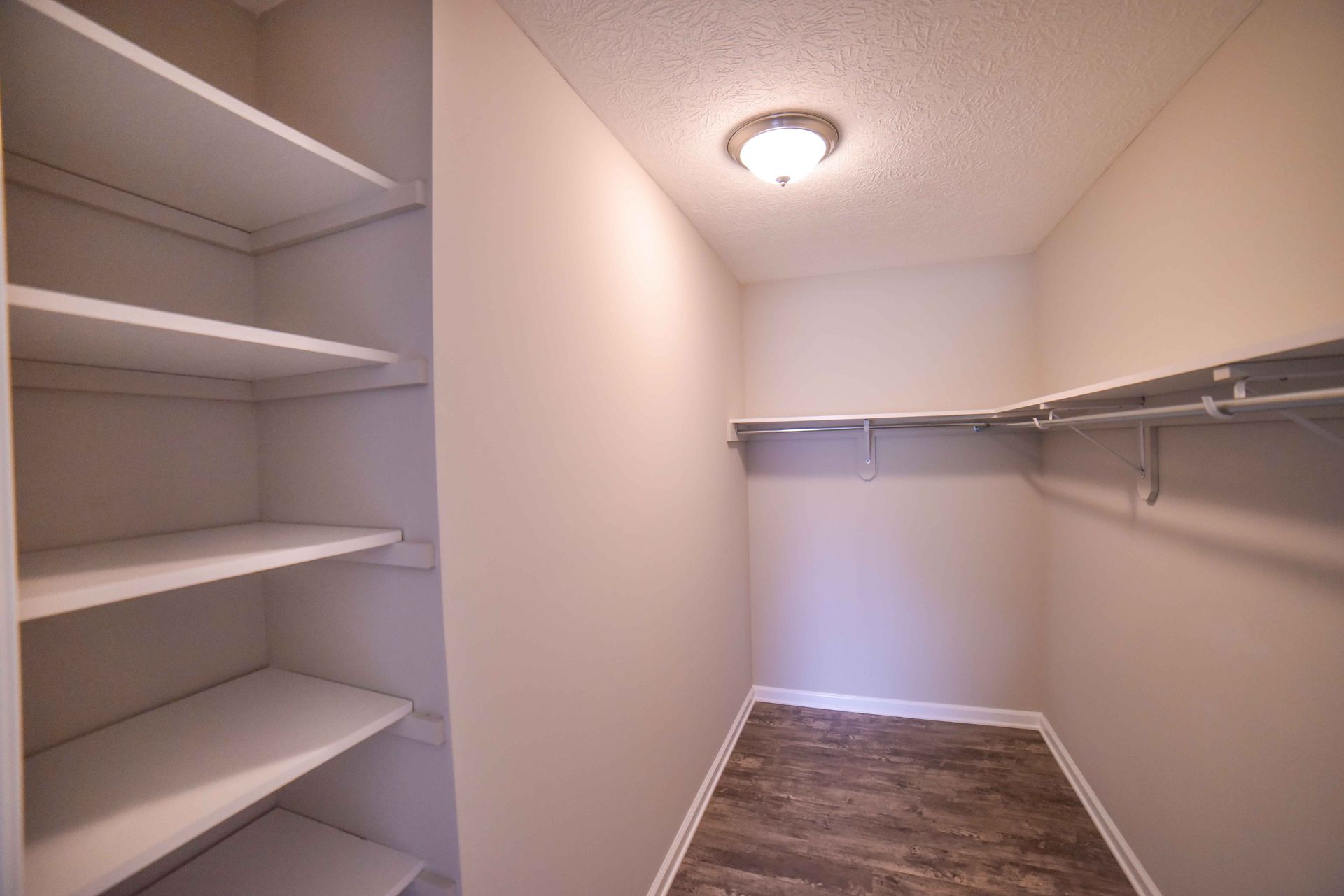 An empty walk in closet with shelves and clothes racks.