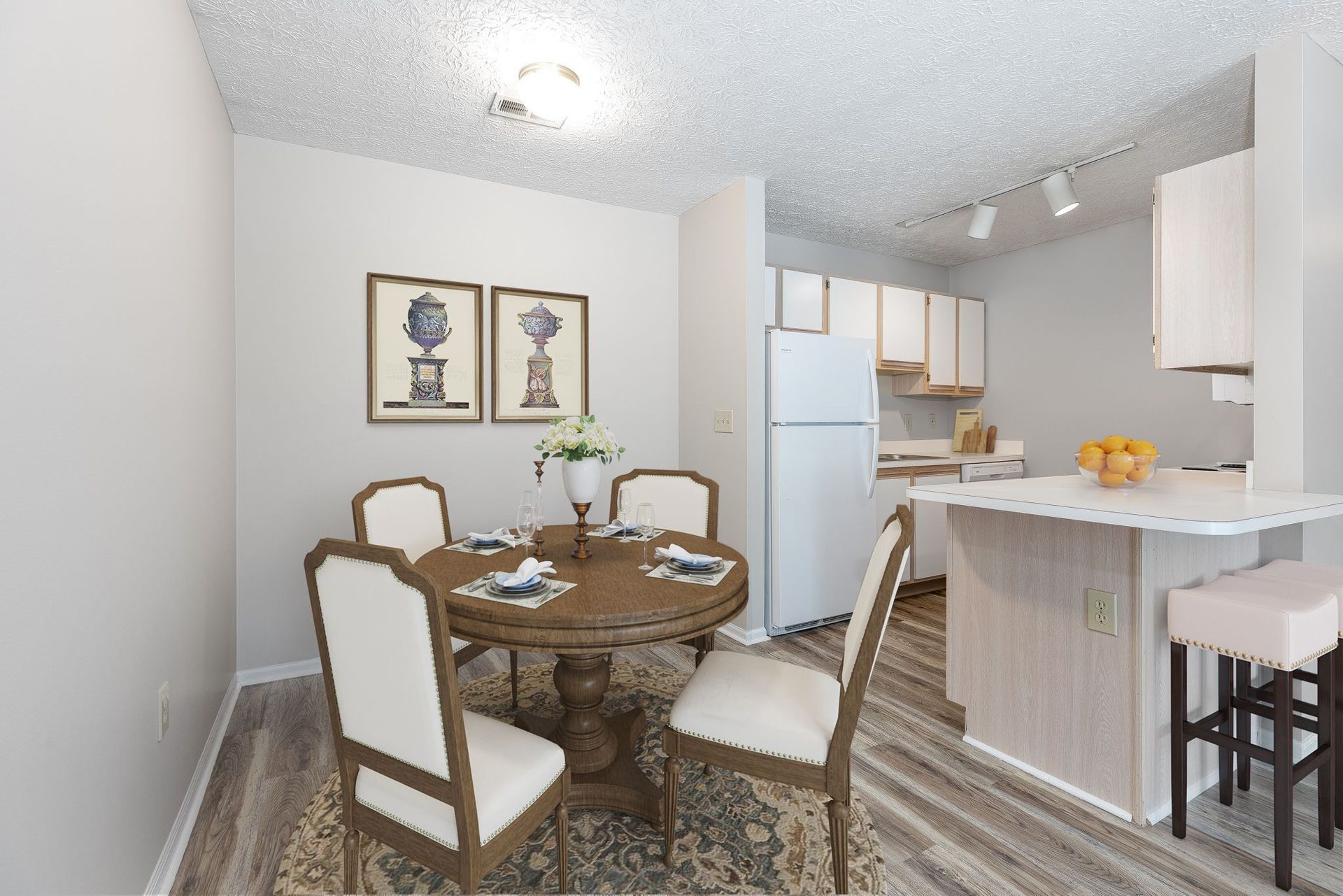 A dining room with a table and chairs and a kitchen in the background.