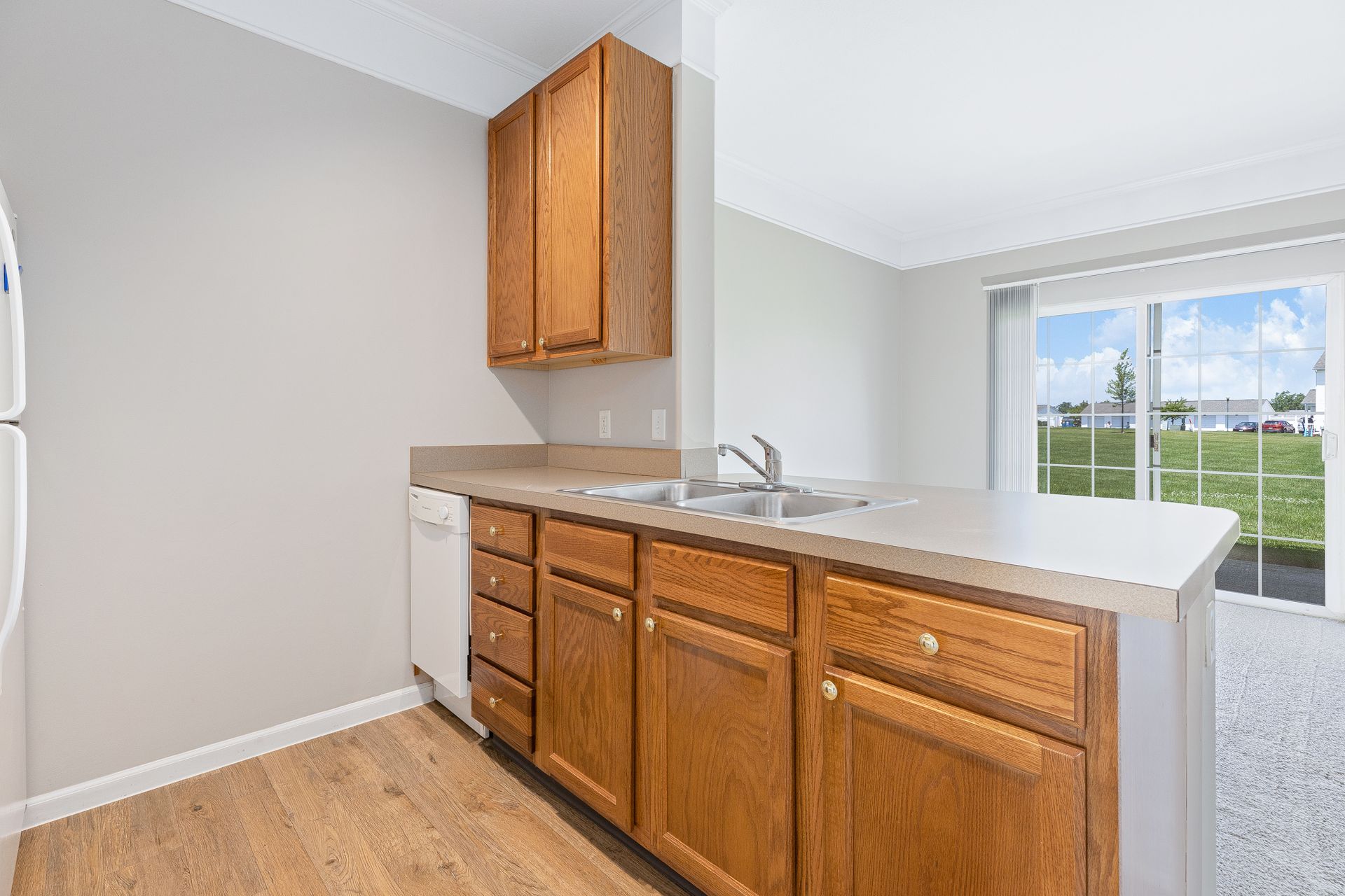 A kitchen with wooden cabinets , a sink , and a refrigerator.