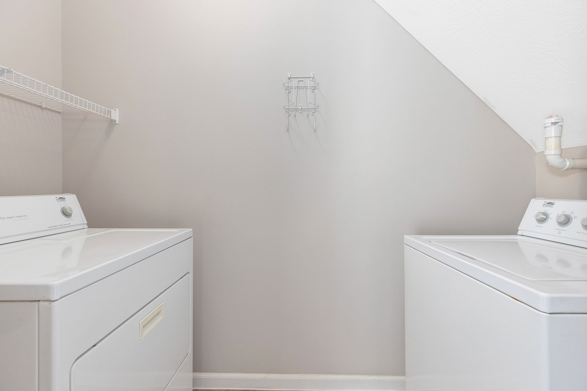 A laundry room with two white washers and dryers.