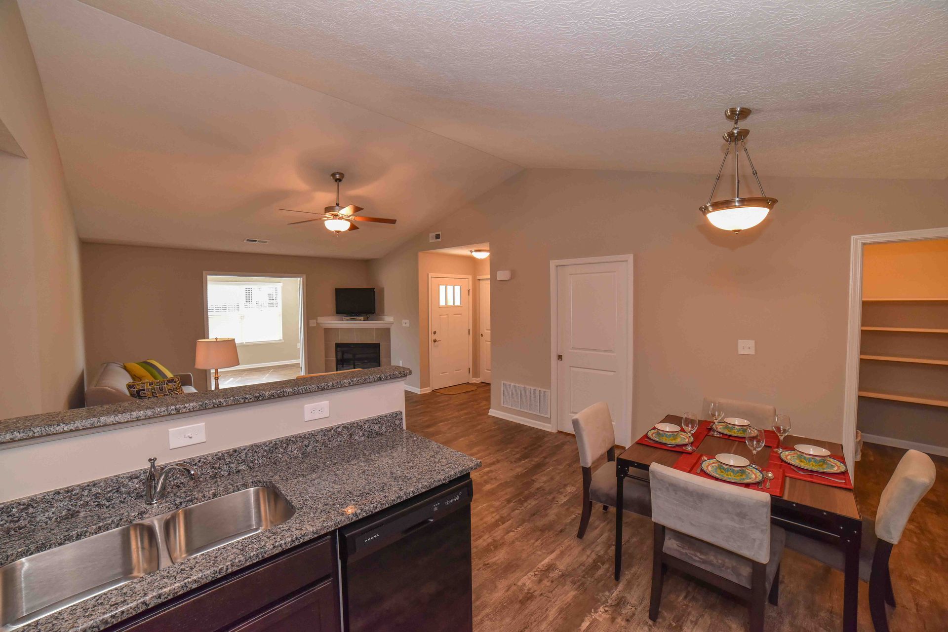 A kitchen with a sink , dishwasher , dining table and chairs.