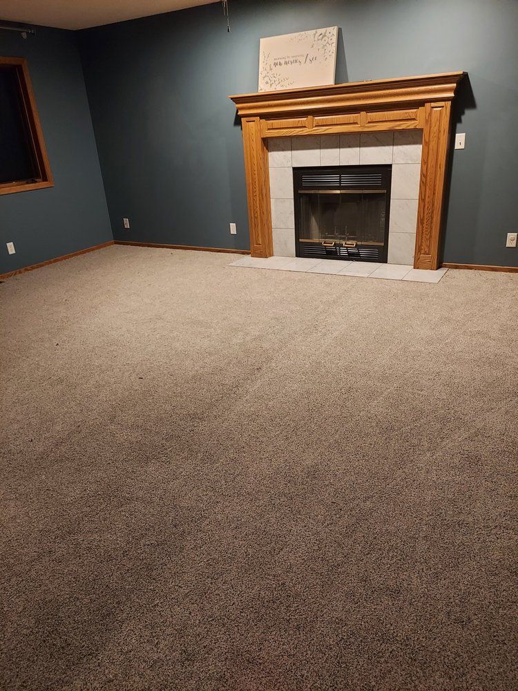Empty room with gray carpet, blue walls, and a wooden fireplace.