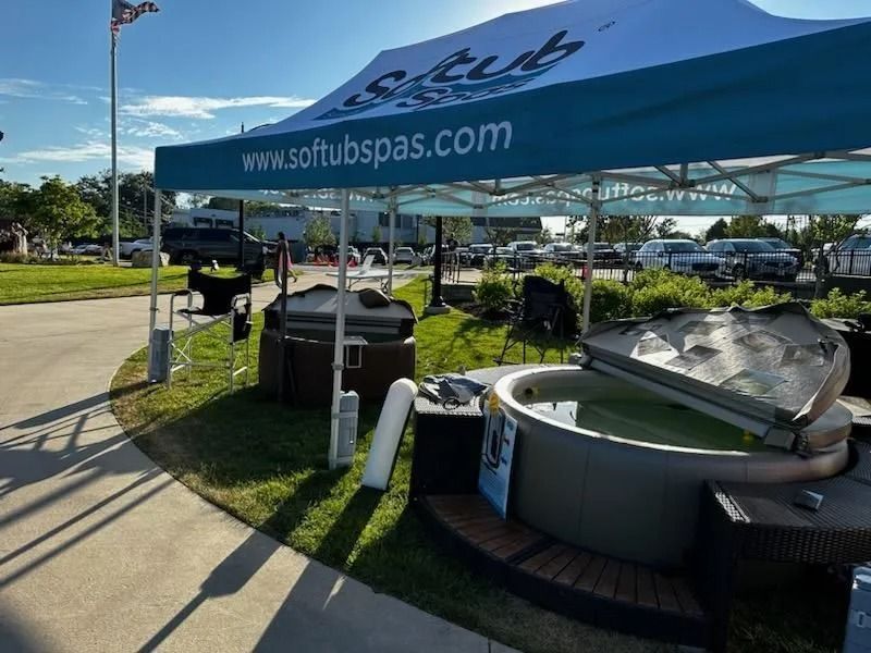 A Softub Spas outdoor display with several hot tubs under a canopy on a sunny day.