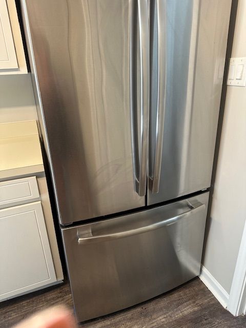 Stainless steel refrigerator with two French doors above a freezer drawer.