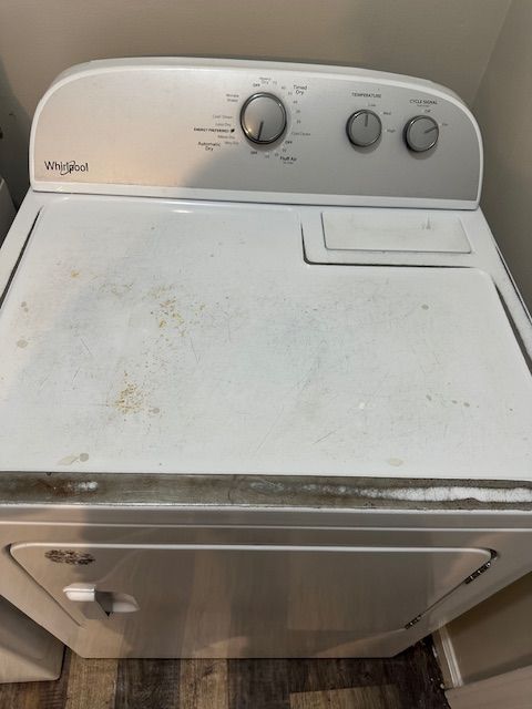 White Whirlpool dryer with controls on top, slightly soiled on the surface.