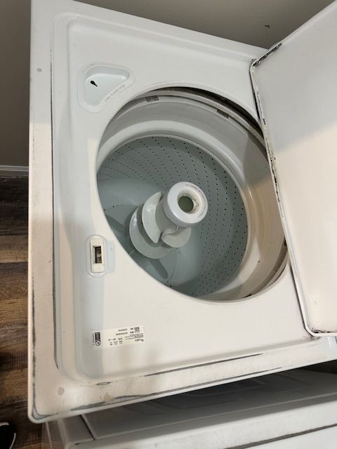 White top-load washing machine with lid open, showing the inner drum and agitator.