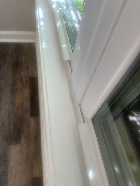 White window frame close-up, showing a seal and partial view of a window on a hardwood floor.