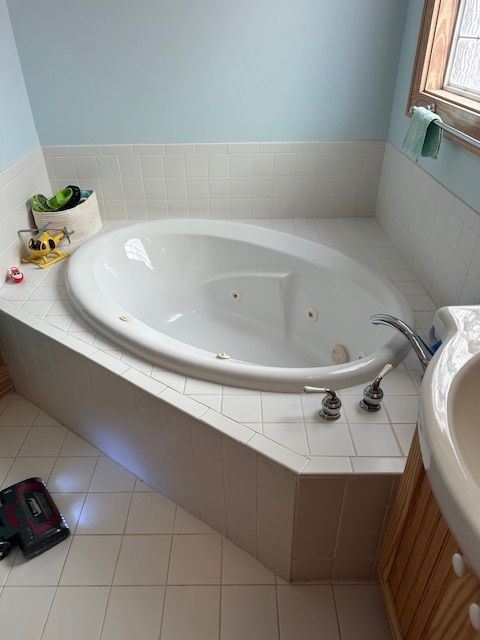 Oval jacuzzi bathtub in a bathroom with light blue walls and tile surround.