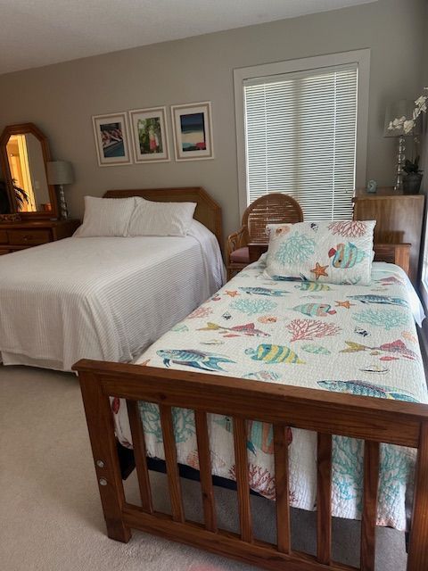 Bedroom with a double bed and a single bed. Both beds have white bedding. Artwork and a window are visible.