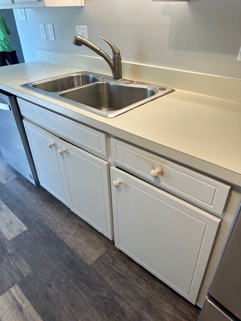 White kitchen cabinets and sink under a white countertop.