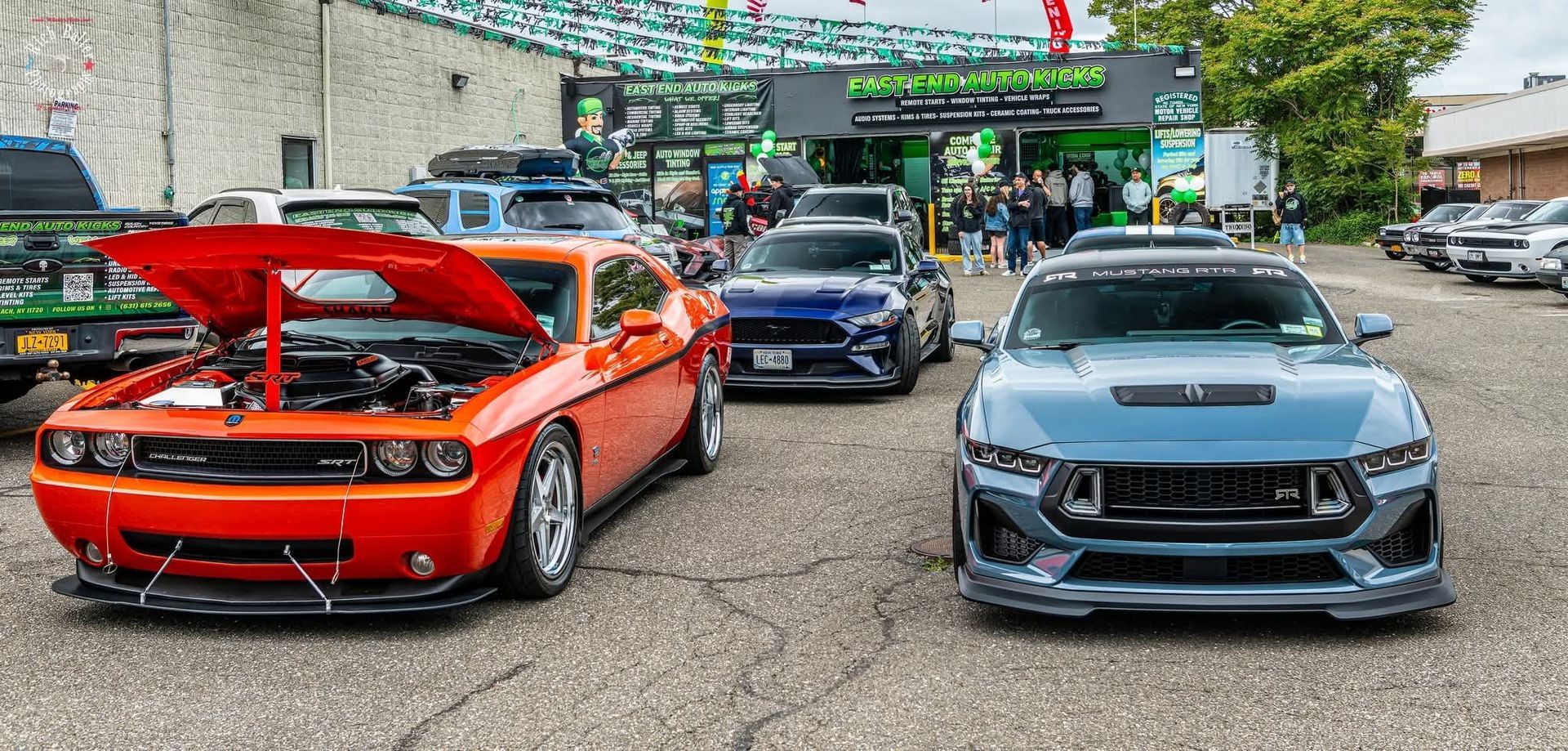Parked sports cars at a car meet, including a red Dodge with hood open and a blue Mustang in front. | East End Auto Kicks