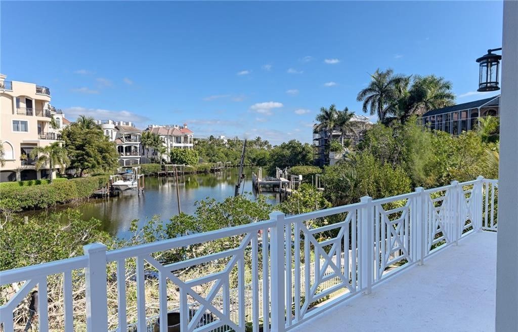 White balcony overlooking a waterway lined with buildings and boats; blue sky.