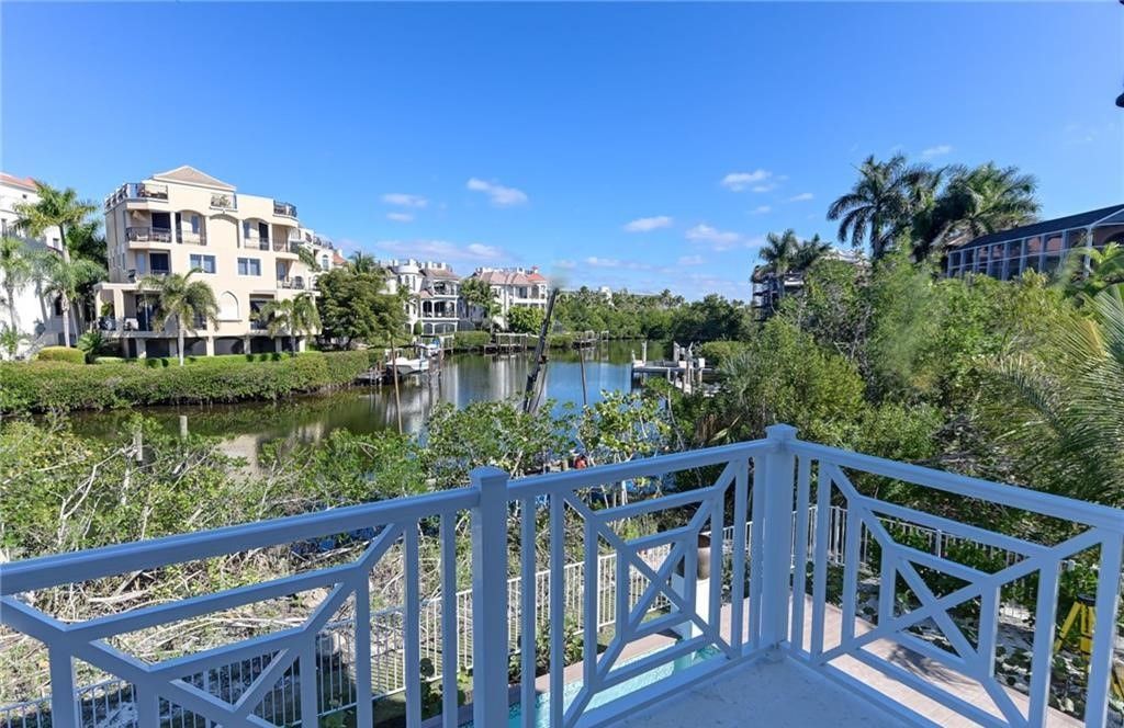 View from a white balcony overlooking a waterway and buildings under a blue sky.