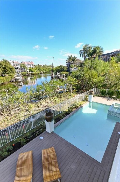 Pool overlooking waterway with boats and homes, sunny day.