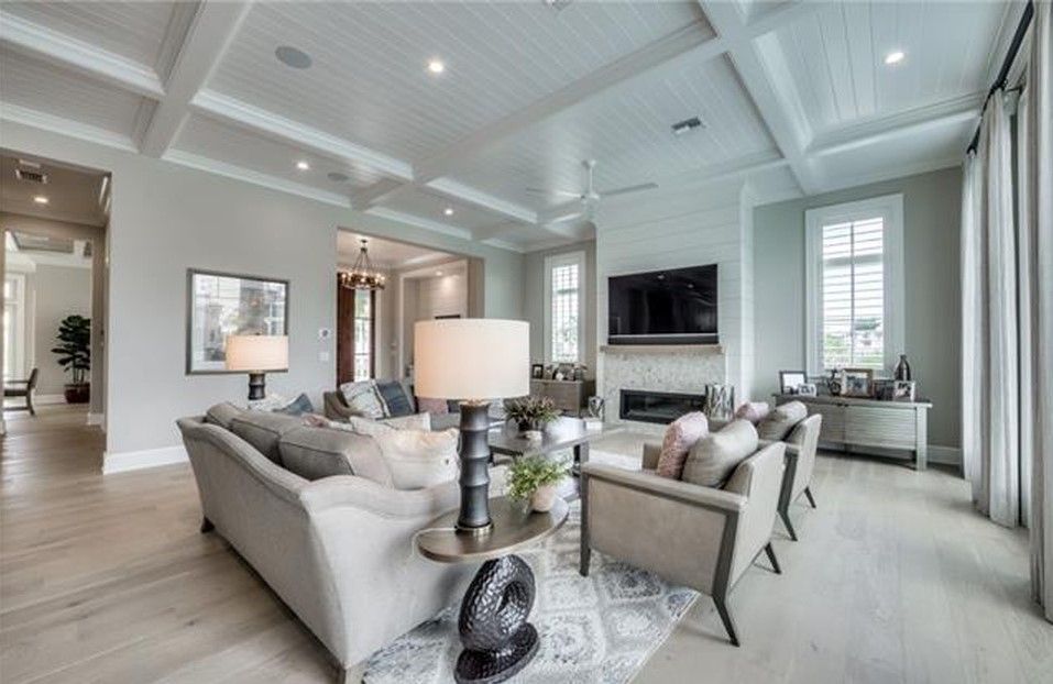 Spacious living room with gray sofas, a fireplace, and light wood floors. White ceiling and walls.