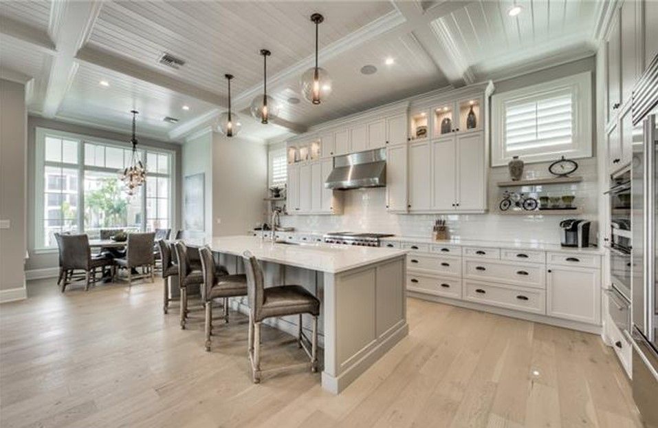 Spacious kitchen with island, white cabinets, stainless steel appliances, and dining area.