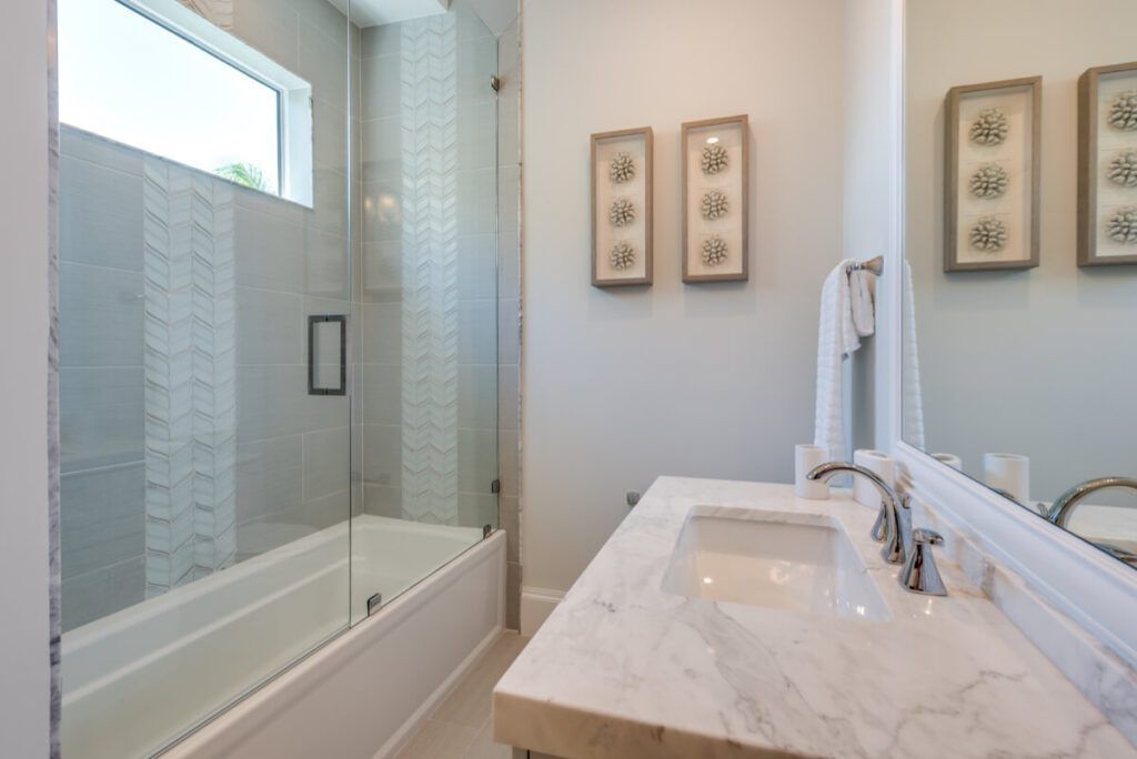 Bathroom with marble countertop, glass shower enclosure, and decorative wall art.