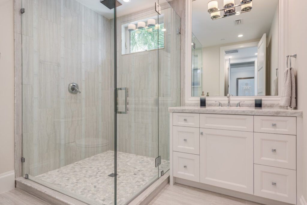 Modern bathroom with glass shower, white vanity, marble countertop, and tiled floor.
