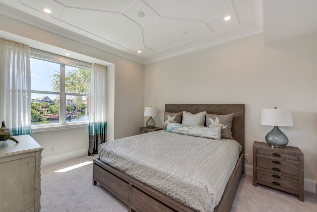 Bedroom with bed, nightstands, window with curtains, and decorative ceiling.