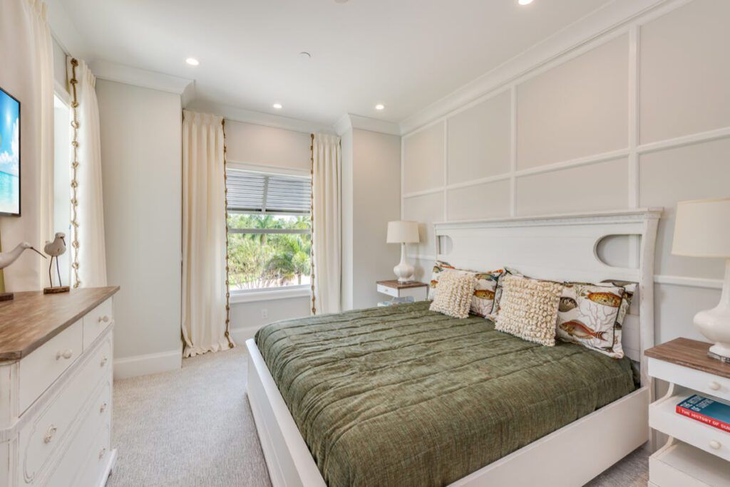 Bedroom with white furniture, olive green bedspread, and window with outdoor view.