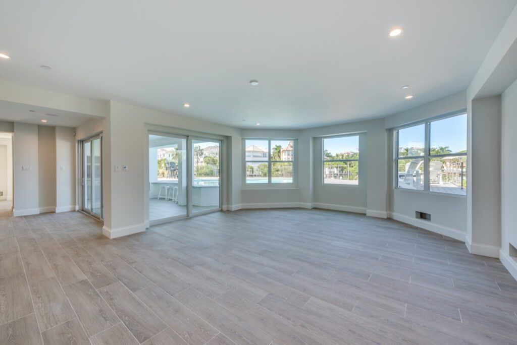 Empty room with gray tiled floor and curved wall of windows. Sliding glass doors lead to a balcony.