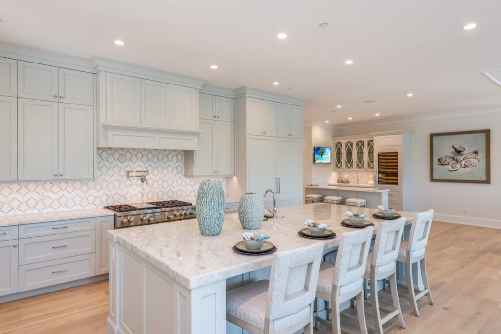 Spacious, light blue kitchen with marble island, bar seating, cabinets, and appliances.