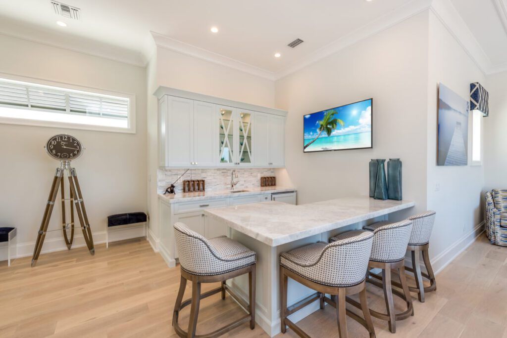 Bar area with marble countertop, stools, cabinets, TV, and decorative items.