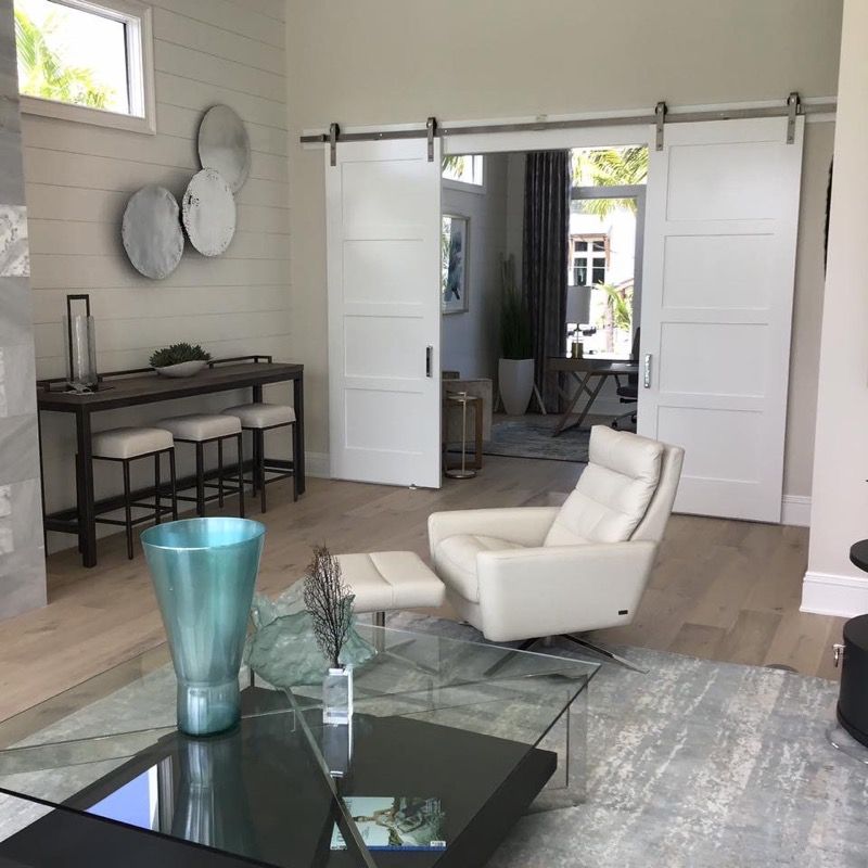 Modern living room with sliding white doors, a light-colored rug, and a white recliner.
