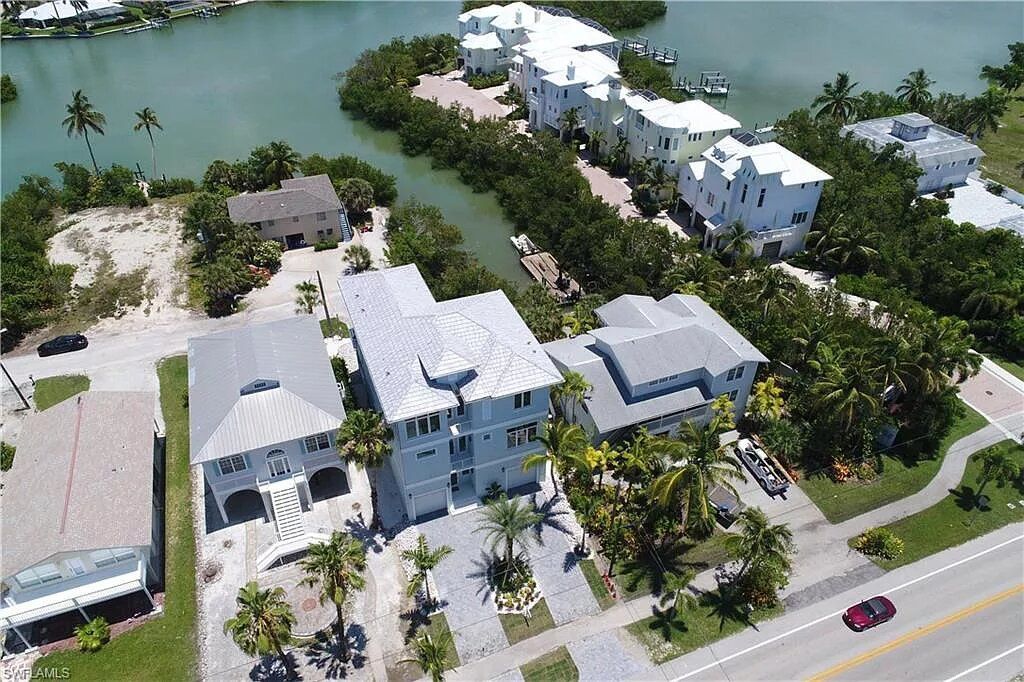 Aerial view of waterfront homes and a canal, sunny day.