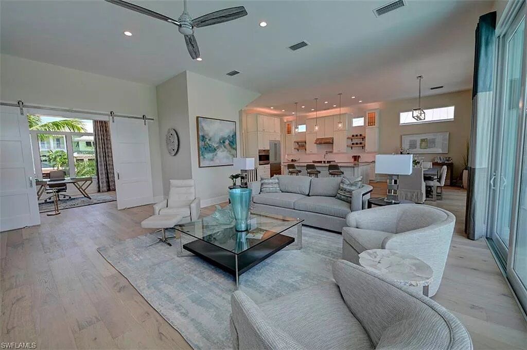 Spacious living room with modern furniture, light wood floors, and open doors to a patio.