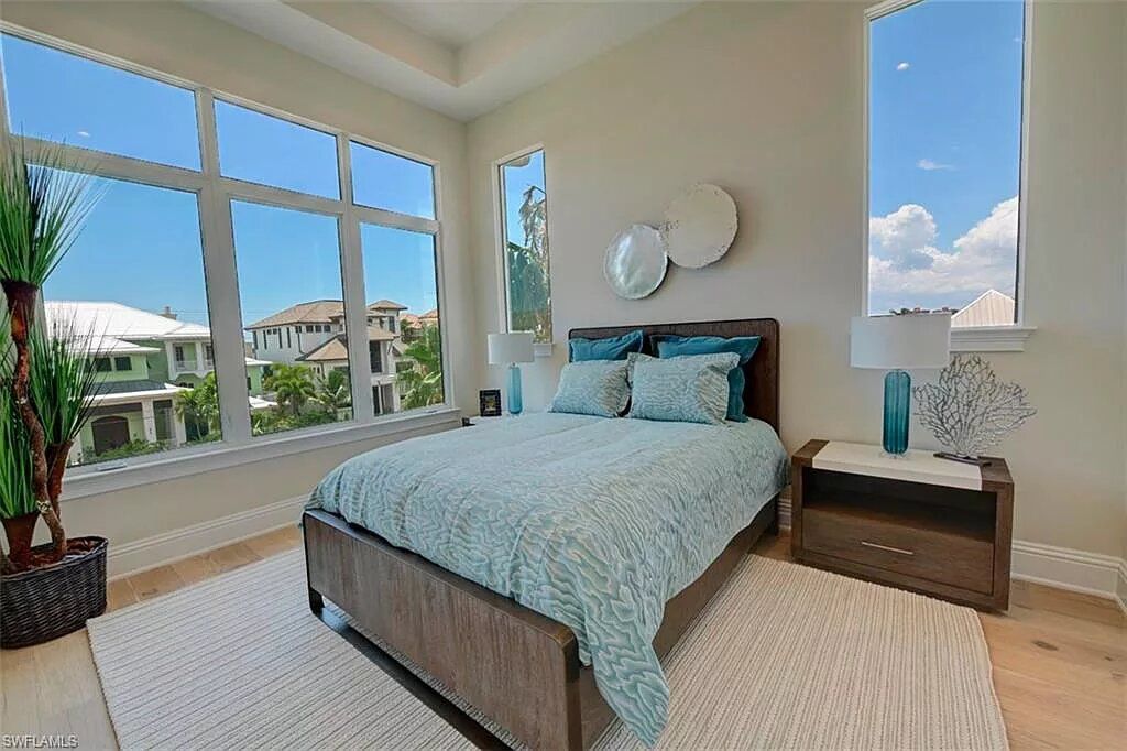 Bedroom with a bed, large windows with a view, and neutral-toned decor.