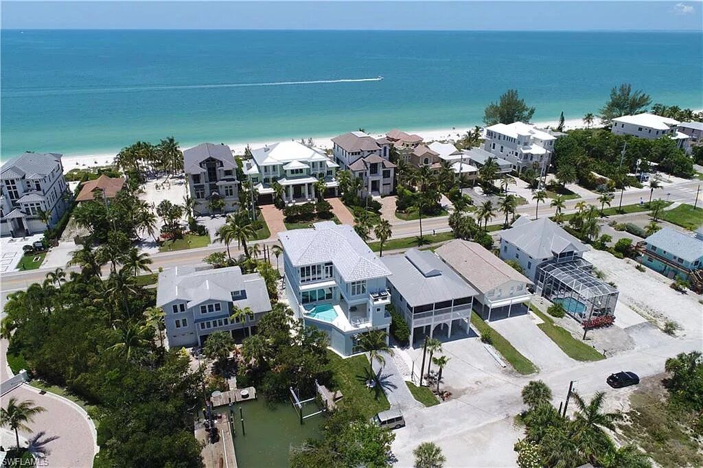 Aerial view of beach houses along a white sandy beach with turquoise water.