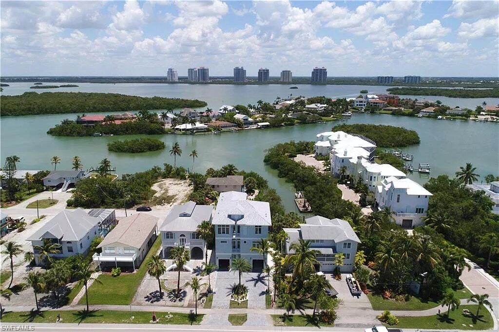 Aerial view of waterfront houses with a city skyline in the background.