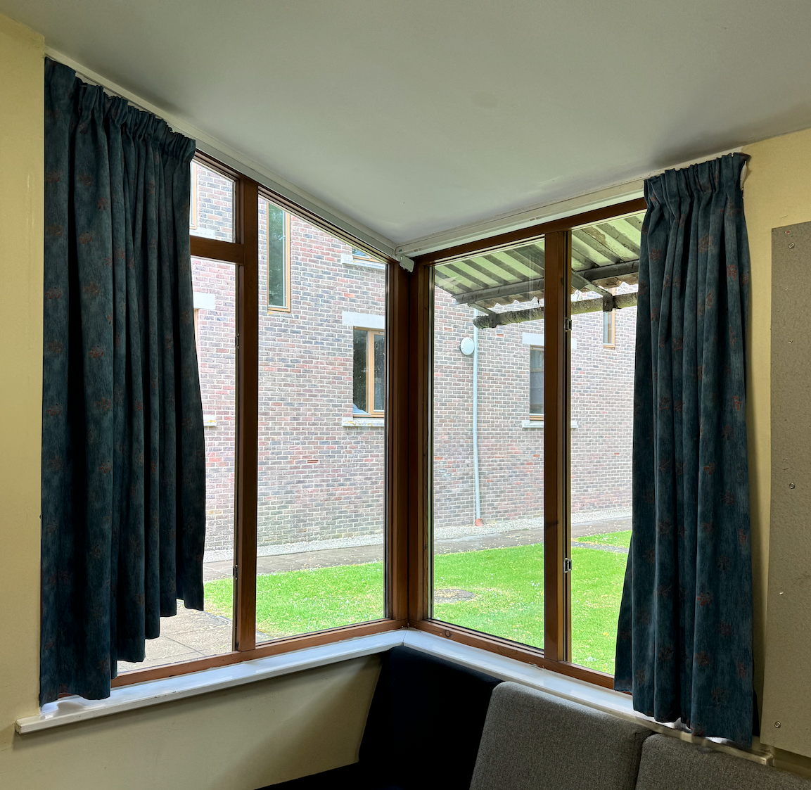 Sloped window with curtains that are too short at one end.