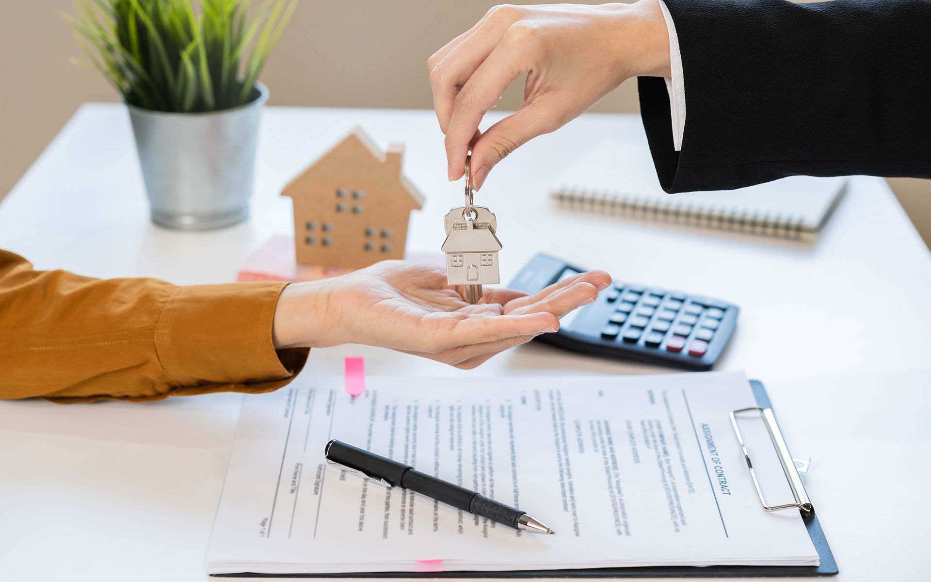 Person handing house keys to another over a contract.