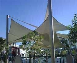 Una gran sombrilla blanca está en el medio de un parque.