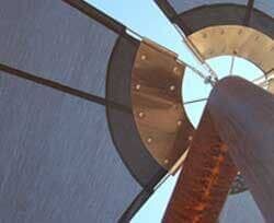 Un primer plano de un molino de viento con un cielo azul de fondo.