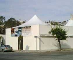 Un edificio blanco con una carpa encima y un auto estacionado frente a él.
