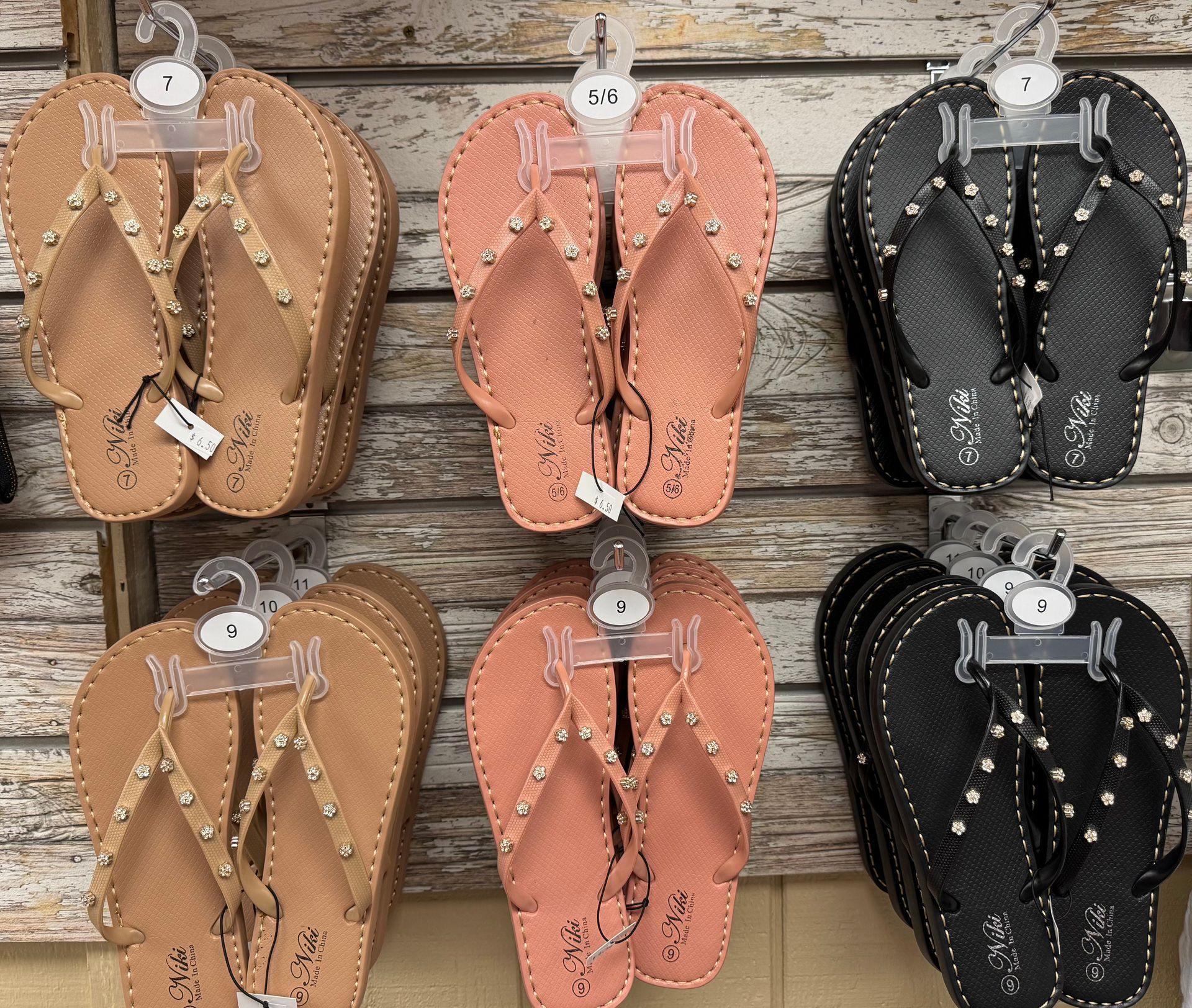 Several pairs of flip flops are hanging on a wall