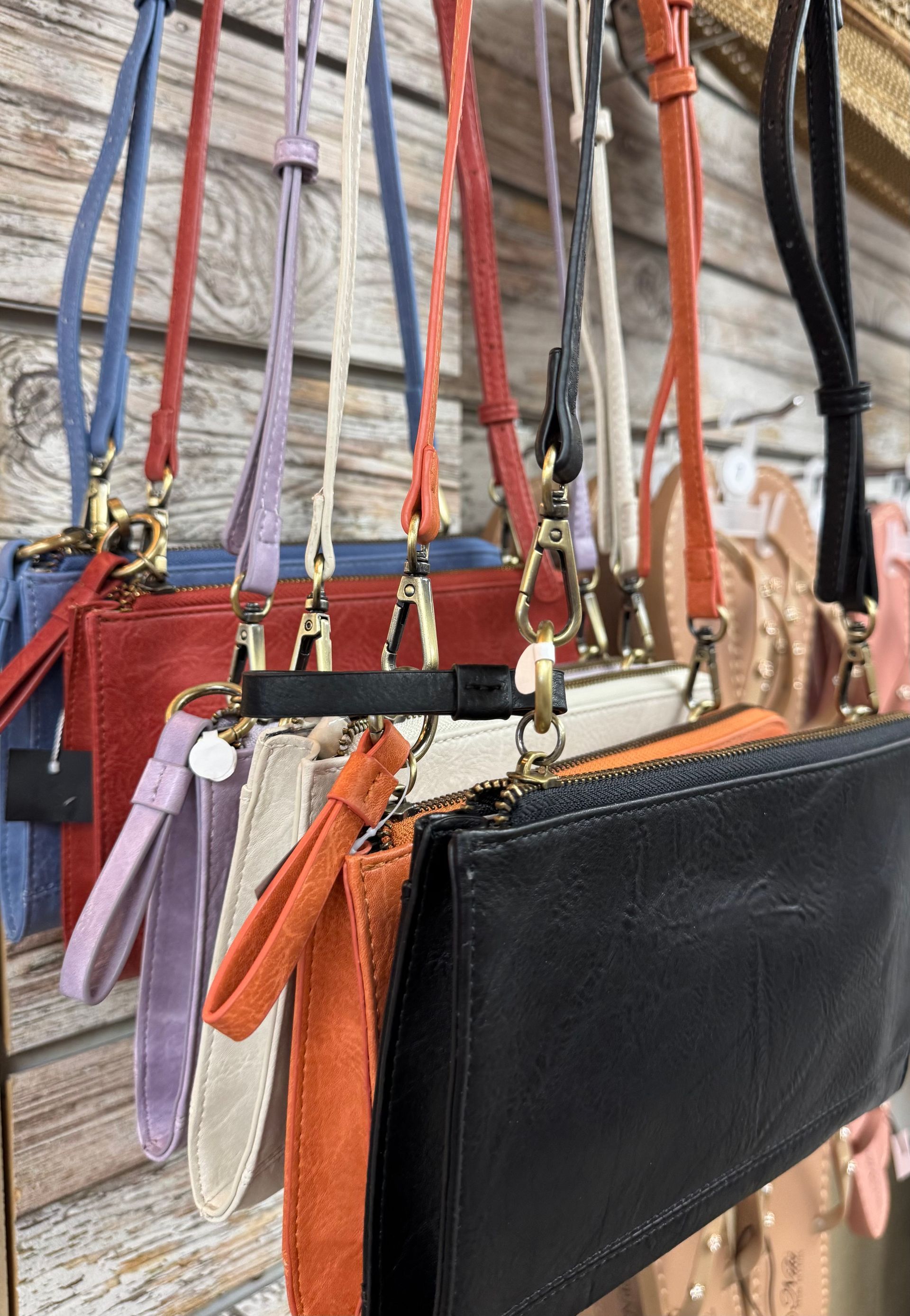 A bunch of handbags are hanging on a wooden wall.