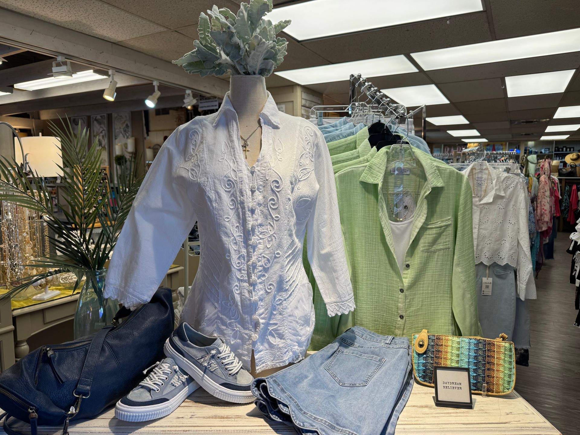 A mannequin is standing in front of a table with clothes on it.