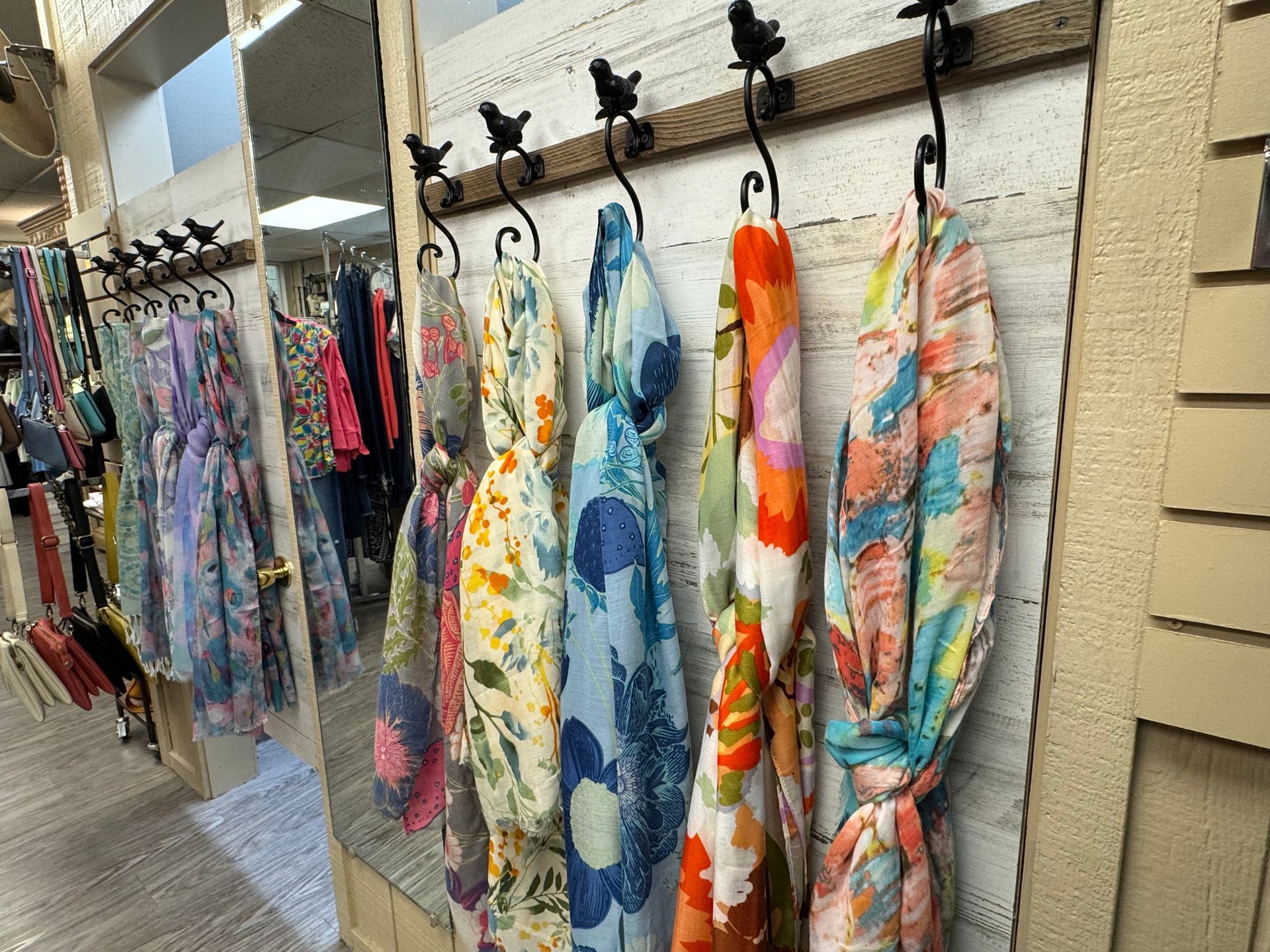 A row of scarves hanging on hooks in a store.