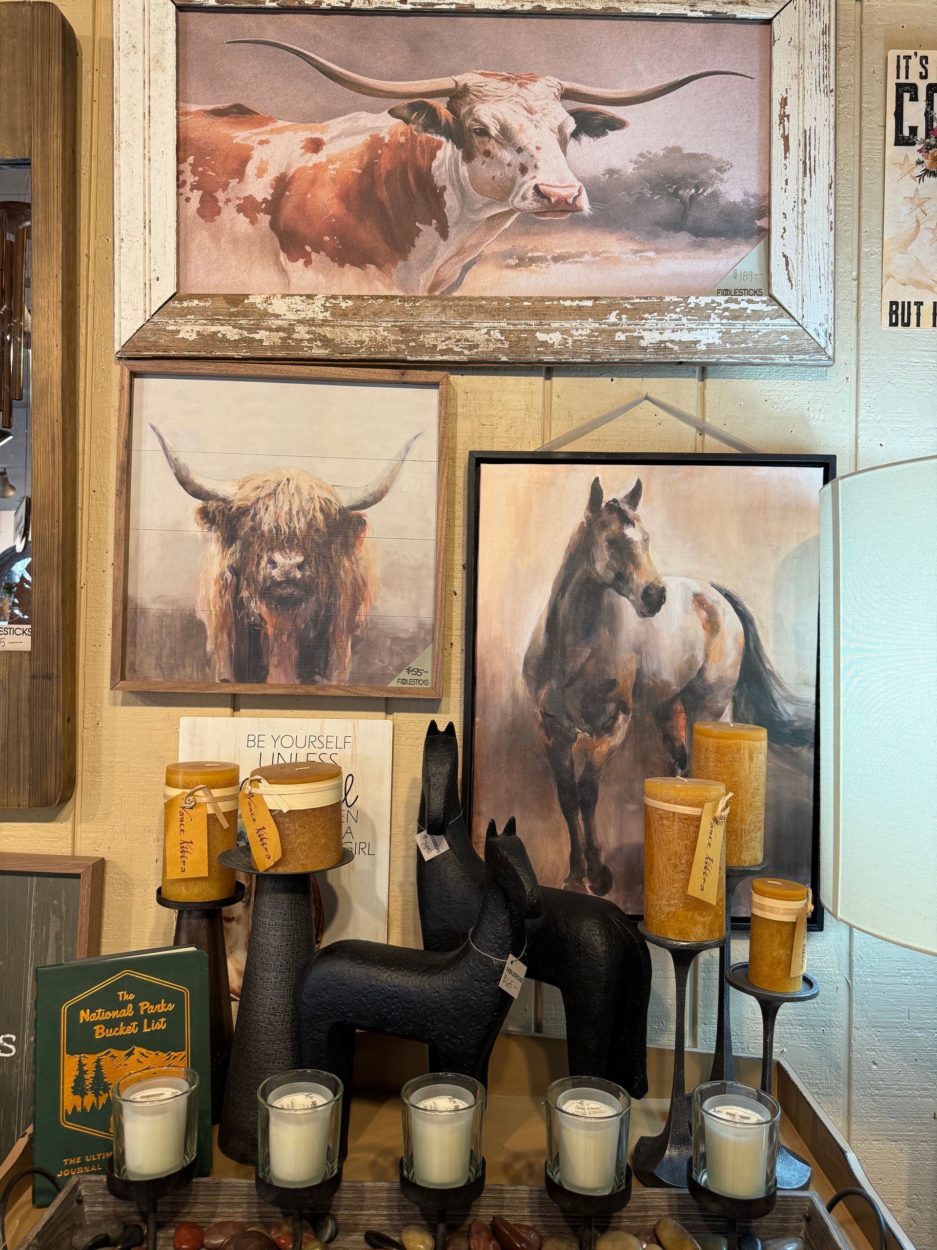 A display of candles and paintings of cows and horses