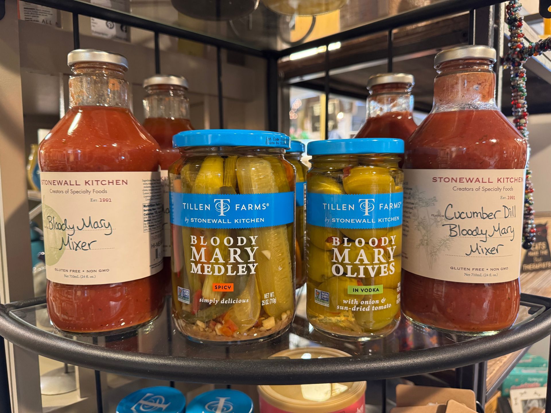A shelf filled with jars of pickles and bottles of tomato sauce.