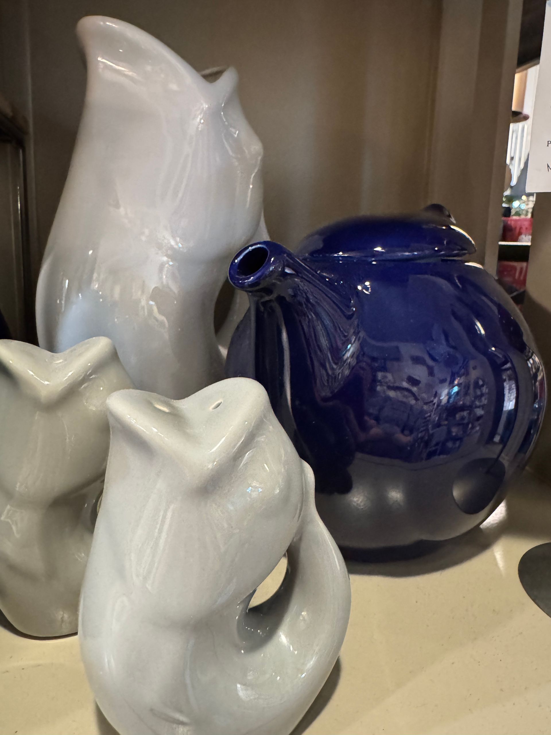 A blue teapot and two white vases are sitting on a table.