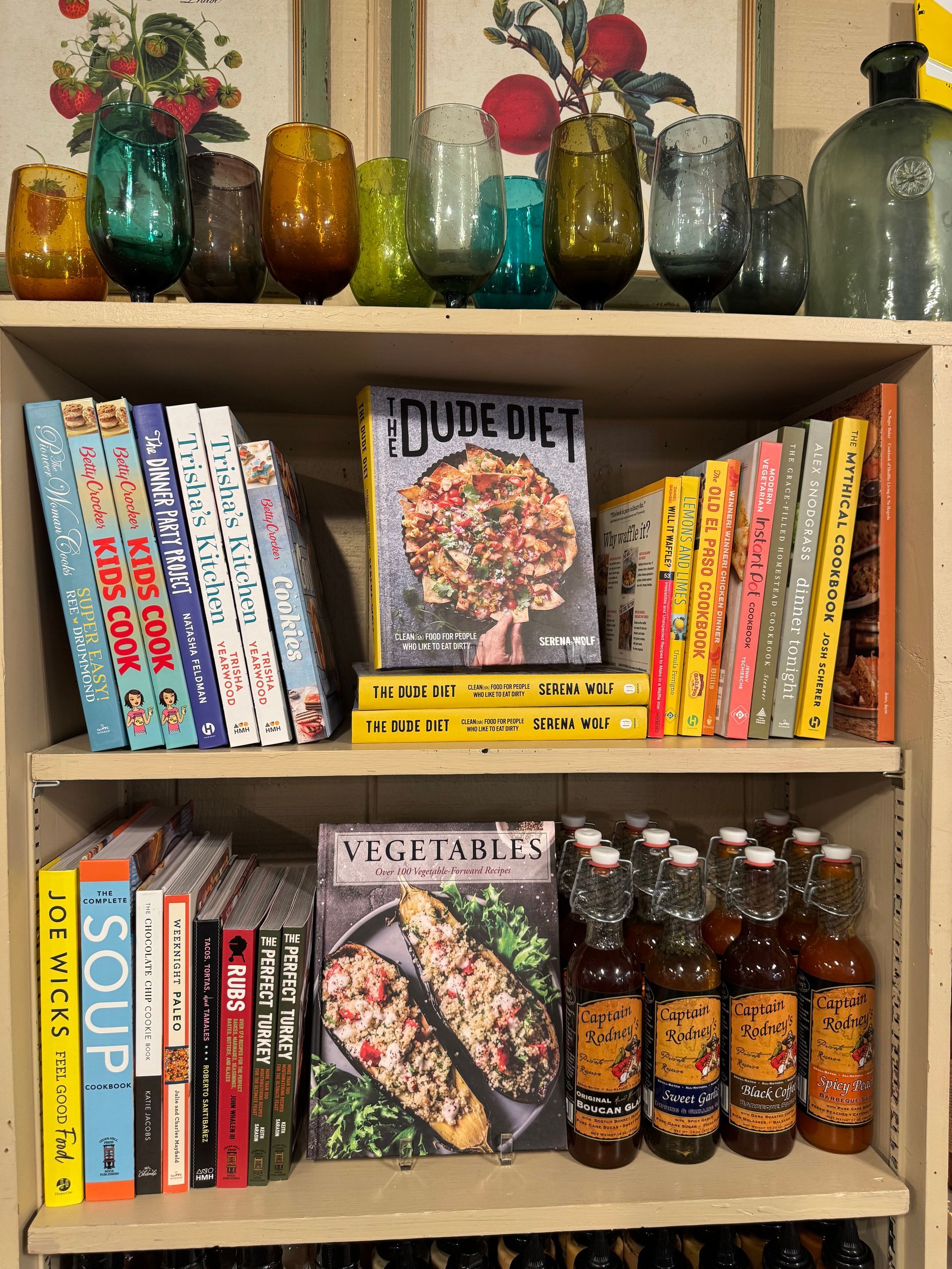 A shelf filled with books and bottles including a dude diet cookbook
