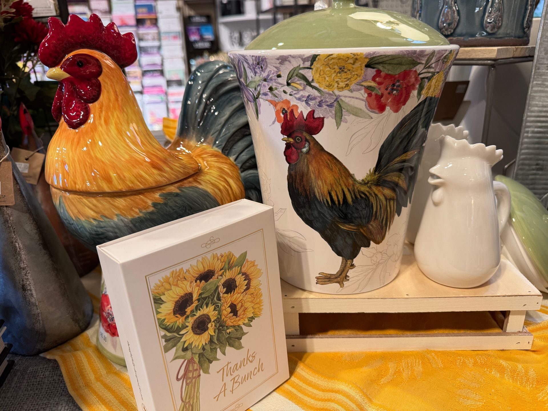 A ceramic rooster is sitting next to a ceramic rooster and a ceramic rooster on a table.