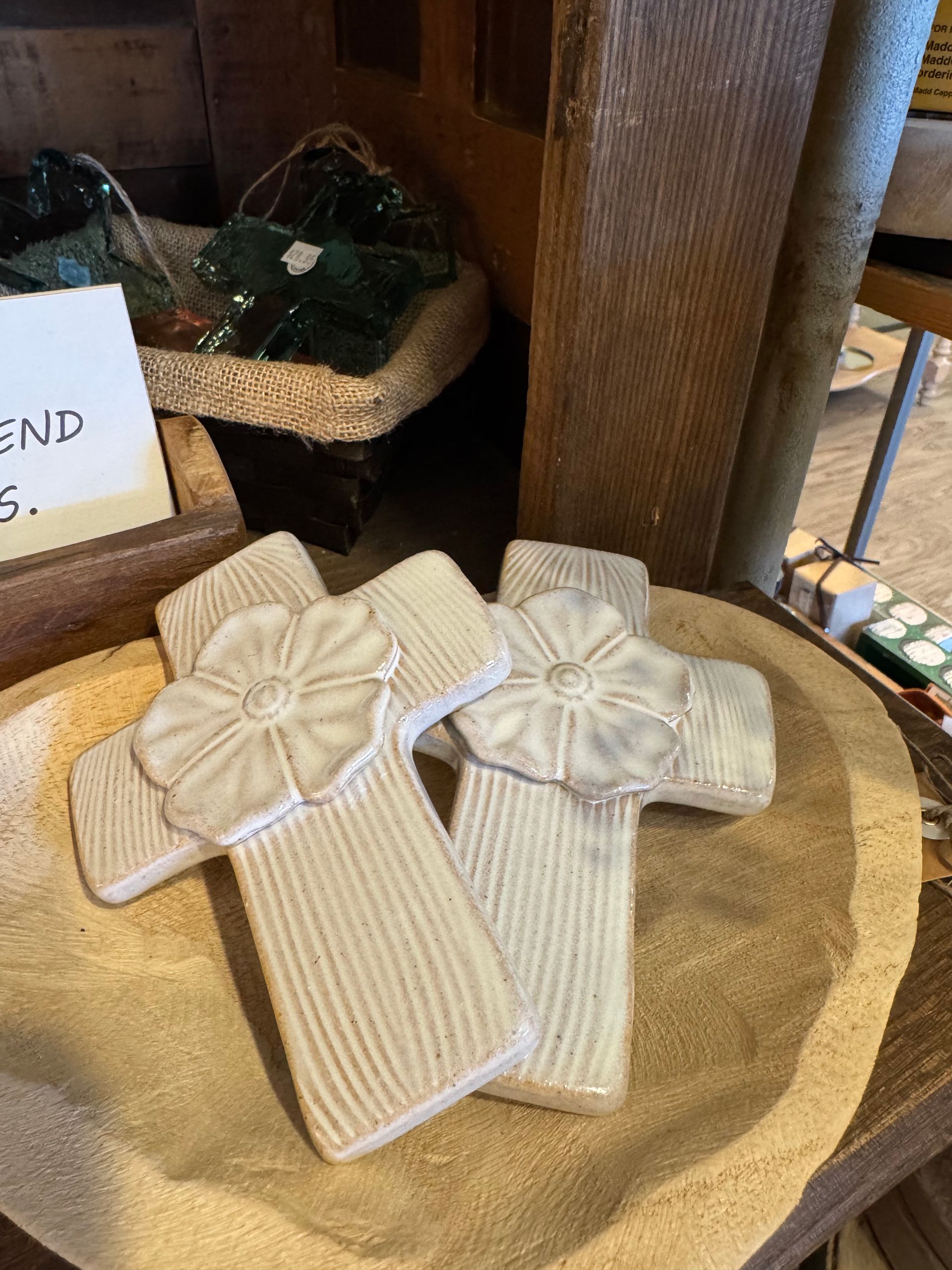 Two white crosses with a flower on them are sitting on a wooden table.