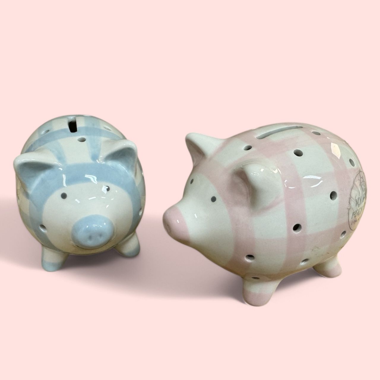 Two piggy banks are sitting next to each other on a pink background